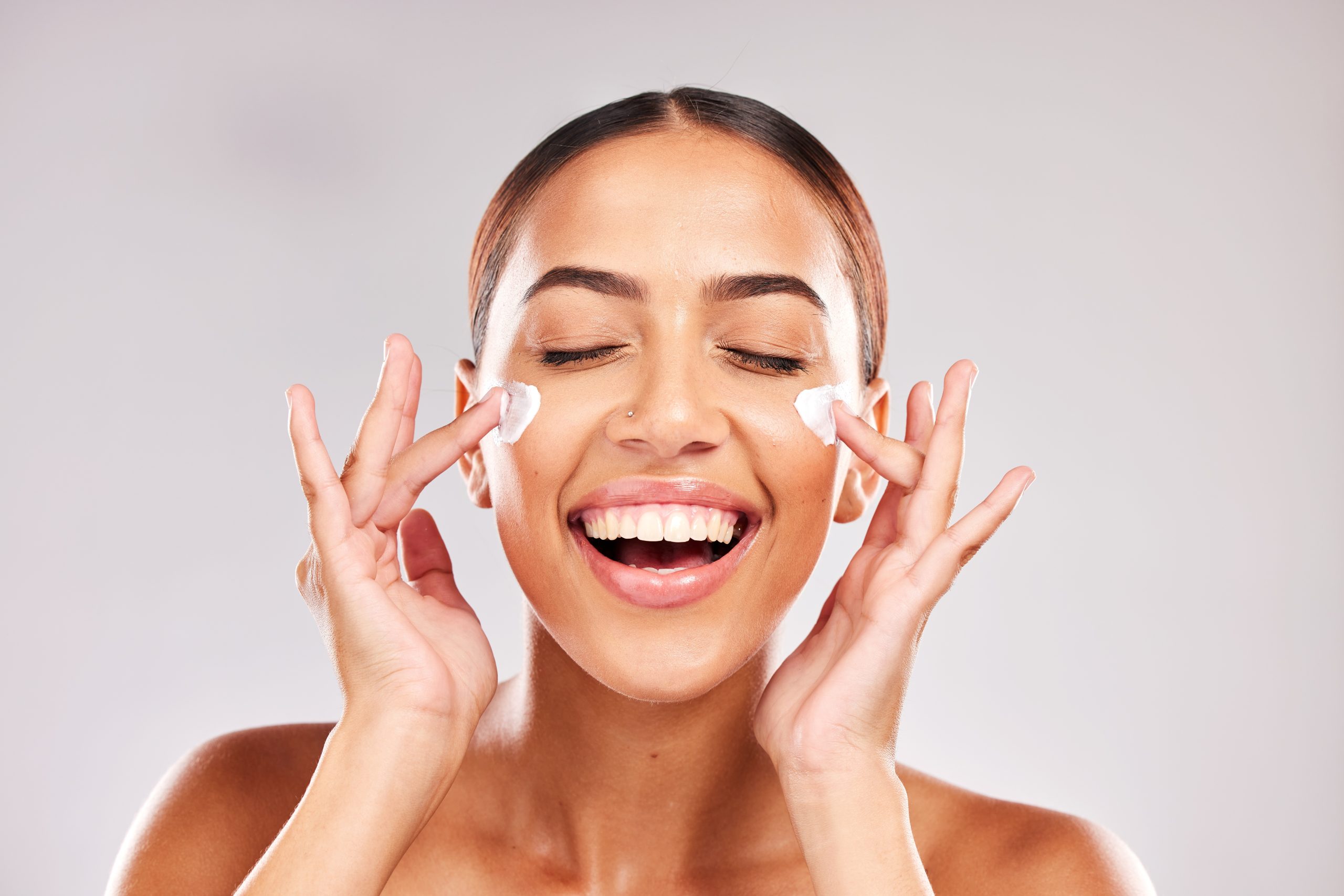 Donna che applica crema solare viso SPF 50 sulle guance durante la skincare